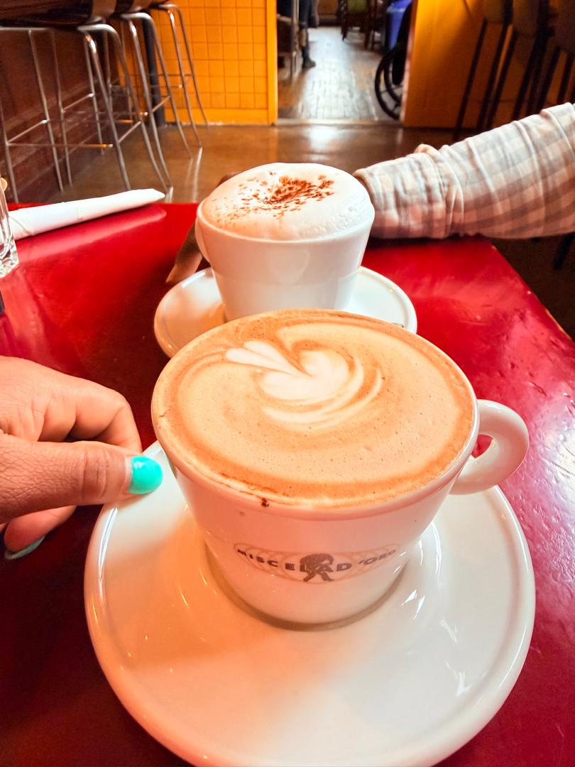 Two cappuccinos on a red café table, a quiet morning conversation